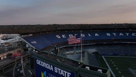 Der-Drohnenschuss-Zeigt-Das-Leere-Georgia-State-Stadium,-In-Dem-Die-Amerikanische-Flagge-Bei-Sonnenuntergang-Weht
