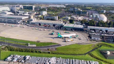 Una-Toma-De-4k-De-Un-Avión-Aterrizando-En-El-Aeropuerto-De-Dublín,-Irlanda,-Que-Muestra-Aparcamientos-Llenos-Y-Aviones-En-La-Pista-Con-Infraestructura-Del-Aeropuerto-Y-Colgadores-De-Mantenimiento.