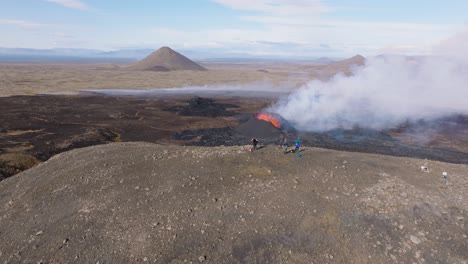 Group-of-adventure-tourist-standing-on-hill-overlooking-active-volcano-eruption