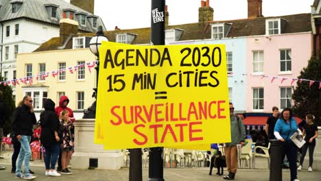 plans-for-2030-to-create-15-minute-cities-which-is-to-have-a-surveillance-state-where-everyone-is-under-control-is-being-constructed-protesters-disagree-with-this-idea-put-up-yellow-signs-to-expose-it