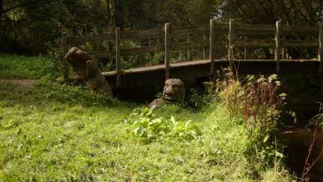 mid-shot-of-wooden-bridge-over-scow-Brook-with-carved-wooden-troll-man-at-bridge-base