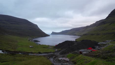 Construction-site-with-sand-mounds-by-coastal-town-of-Arnafjordur-in-Bordoy,-Faroe-Islands