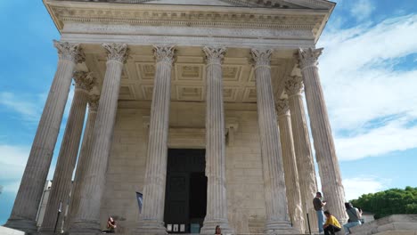 very-beautiful-architectural-stone-building-with-columns,-a-hexastyle-roman-temple,-"the-square-house"-famous-for-heritage,-in-a-town-in-the-south-of-France-with-people-in-front,-many-steps