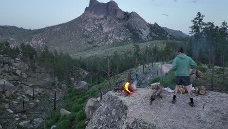 Friends-makes-campfire-on-boulder-with-views-of-Sheeprock,-San-Isabel