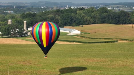 Drohnenaufnahme-Eines-Heißluftballons,-Der-In-Der-Luft-über-Landwirtschaftlichen-Feldern-Am-Rande-Einer-Stadt-Schwebt,-Luftaufnahme