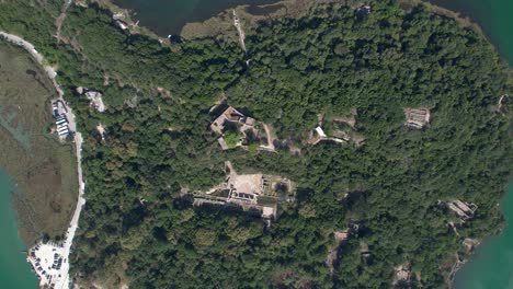 Butrint-Hill-with-Amphitheater,-Tower,-Church-Ruins,-and-Gladiator's-Buildings-in-the-Ancient-Roman-City's-Spectacular-Landscape,-Aerial