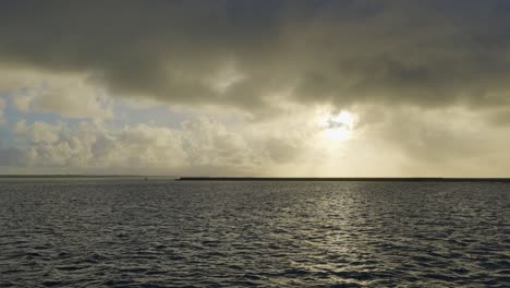 Aus-Der-Perspektive-Eines-Wasserfahrzeugs-Entsteht-In-Einer-Weitläufigen-Panoramaszene-Ein-Bild-Kolossaler-Sonnenuntergangswolken,-Die-Von-Göttlichen-Strahlen-Beleuchtet-Werden