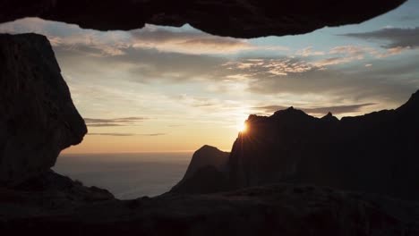 Peeking-at-the-sunset-through-mountain-cracks-in-Hesten,-Norway