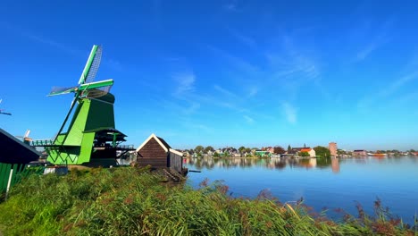 Green-Dutch-mill-next-to-Zaan-river-and-village-houses-at-Zaanstad