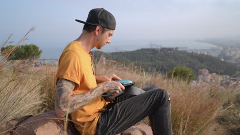 Drone-pilot-men-looking-at-aerial-footage-with-laptop-on-top-of-mountain