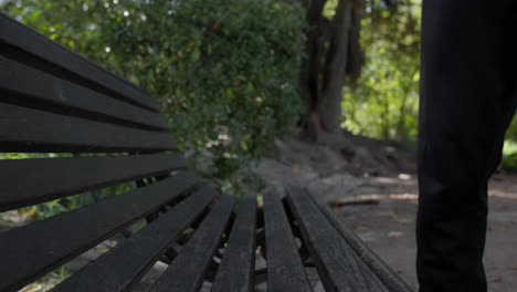 A-man-sitting-down-on-a-park-bench,-medium-close-up