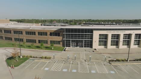An-aerial-establishing-shot,-moving-left-to-right,-of-Clear-Lake-High-School-in-Houston-Texas-on-a-sunny-morning-with-clear-blue-sky-behind-this-modern-architecture-education-building