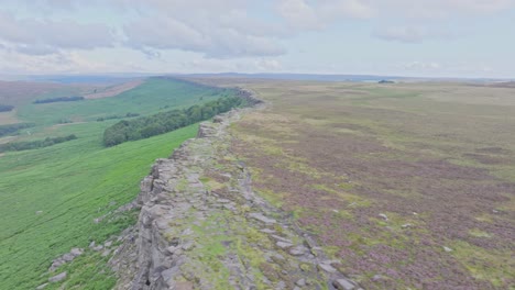 Drone-flies-left-to-right-over-Stanage-Edge-rock-escarpment-on-cloudy-day