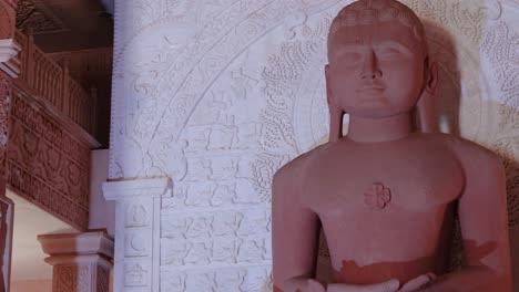 Estatua-Sagrada-Del-Dios-Jainista-De-Piedra-Roja-Aislada-En-Meditación-Desde-Diferentes-ángulos-El-Video-Se-Toma-En-Shri-Digamber-Jain-Gyanoday-Tirth-Kshetra,-Nareli-Jain-Mandir,-Ajmer,-Rajasthan,-India