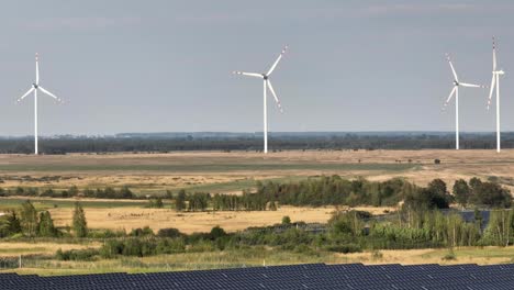aerial-established-of-green-renewable-clean-energy-production-with-solar-panel-photovoltaic-base-station-and-wind-turbine-at-distance