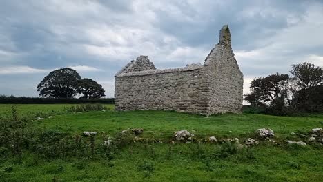 The-ruins-of-Capel-Lligwy-on-rural-Moelfre-countryside,-Anglesey,-North-Wales,-Slowly-panning-right