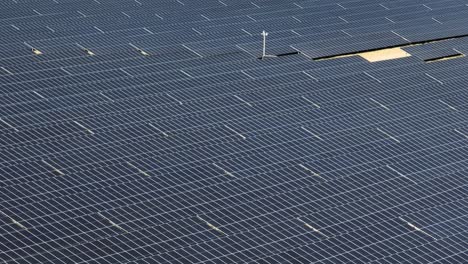 Solarpanel-Luftaufnahme,-Die-Einen-Grünen-Bauernhof-Für-Erneuerbare-Energien-Mit-Windmühlenturbine-In-Einer-Natürlichen,-Unverschmutzten-Grünen-Landschaft-Zeigt