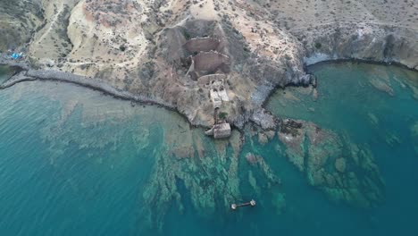 Aerial-perspective-unveils-the-abandoned-iron-mine-and-deteriorated-port,-now-haunting-ruins-beside-the-sea