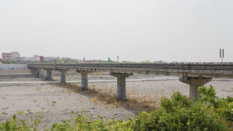 Eine-Lange-Straßenbrücke,-Die-Unter-Einem-Bewölkten-Sommerhimmel-Im-Süden-Taiwans-über-Einen-Großen-Ausgetrockneten-Fluss-Führt-–-Totalaufnahme
