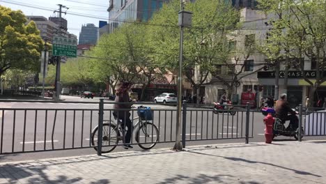 Mujer-China-En-Bicicleta-Por-Las-Calles-De-Shanghai,-China-En-Cámara-Lenta