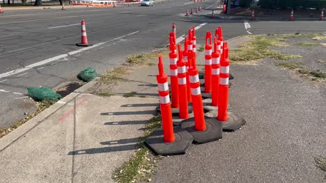 Safety-cones-gathered-onto-the-sidewalk-next-to-an-asphalt-road