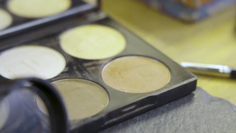 Makeup-brush-dipping-into-a-cosmetic-palette-at-the-beauty-salon