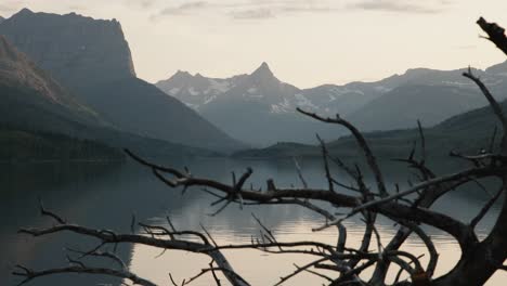 Lago-Escondido-Y-Montañas-Rocosas-De-Montana-Vistas-A-Través-De-Ramas-Sin-Hojas,-Parque-Nacional-Glacier