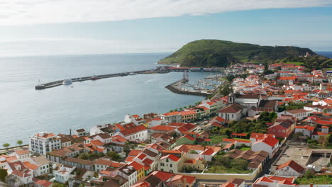 Cinematic-aerial-drone-shot-of-picturesque-local-town-of-Horta-in-Faial-island,-Azores---Portugal-High-view-of-the-ships-docked-at-the-harbor,-green-landscape-in-the-background