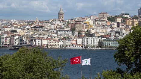 Bandera-De-Turquía-Ondeando-Al-Viento,-Torre-De-Gálata-Al-Fondo,-Estambul,-Turquía