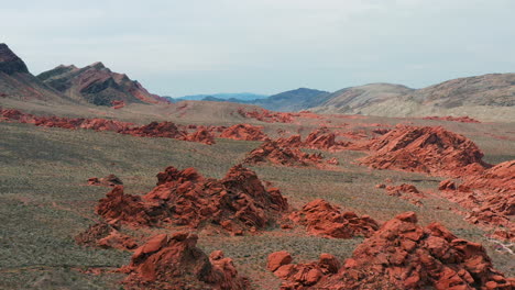 Aerial-view-in-front-of-red-rocks-in-the-deserts-of-Nevada,-partly-sunny-USA