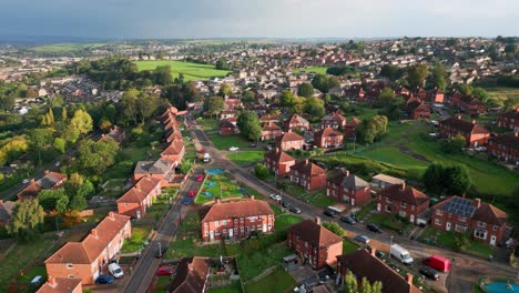 Urban-housing-in-the-UK:-Red-brick-council-estate-in-Yorkshire,-aerial-drone-view,-bathed-in-morning-sun,-with-homes-and-people