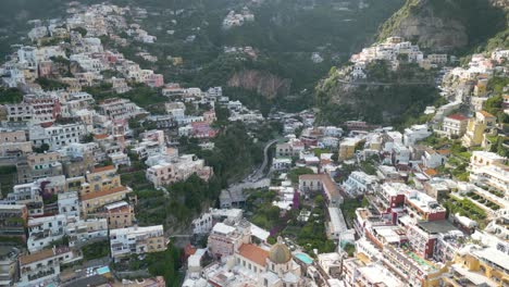 Eine-Drohnenaufnahme-Von-Hinten-Zeigt-Die-Stadt-Positano,-Die-In-Die-Klippen-Der-Amalfiküste-Gebaut-Ist