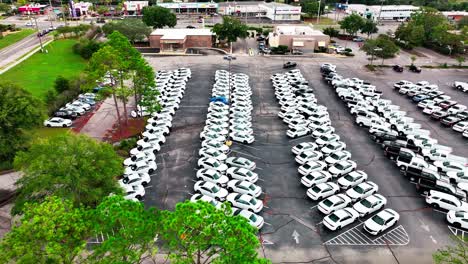 Coches-De-Policía-Camuflados-En-El-Estacionamiento,-Tiro-Aéreo-Con-Drones,-Transporte-En-Camión-A-La-Derecha.