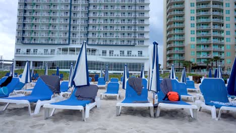 Beach-chair-and-umbrella-on-the-Beach-for-tourist-relaxation-with-hotel-building-in-the-background