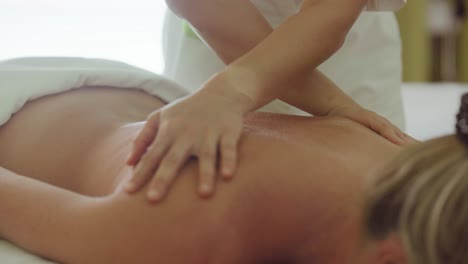 Masseuse-rubbing-back-of-woman-during-relaxing-massage-in-salon