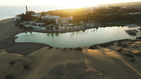 Maspalomas-dunes,-Gran-Canaria:-aerial-view-flying-over-the-dunes-and-spotting-the-Maspalomas-pond-and-the-lighthouse