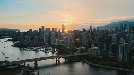 Aerial-establishing-shot-of-Vancouver-Island-with-downtown,-skyscraper-and-driving-cars-on-bridge-during-sunset-time