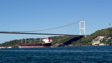 Cargo-Ship-Passing-Under-Fatih-Sultan-Mehmet-Bridge,-Bosphorus,-Istanbul,-Turkey