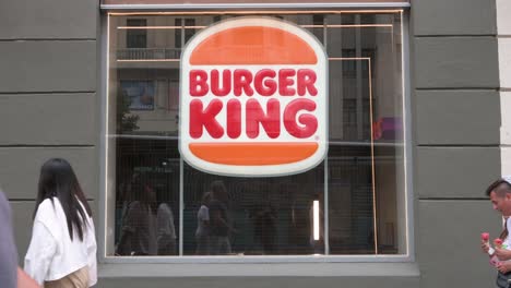 Pedestrians-and-shoppers-walk-past-the-American-chain-of-hamburger-fast-food-restaurant-company-Burger-King-in-Spain