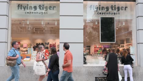 Women-window-shopping-at-the-Danish-gift-chain,-Flying-Tiger-Copenhagen,-store-as-pedestrians-walk-past-the-frame