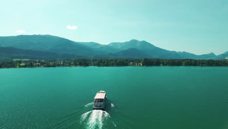 Drone-follows-and-then-flies-by-a-boat-moving-across-the-turquoise-waters-of-Wolfgangsee-Lake