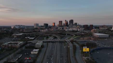 Downtown-Atlanta-Freeway,-Interchange-with-iconic-skyline-and-skyscrapers-in-the-background-under-sunset-sky,-Aerial-View