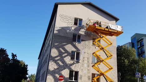 Maler-Machen-Auf-Einer-Scherenhebebühne-Coole-Zeichnungen-An-Einem-Haus-In-Tartu,-Estland