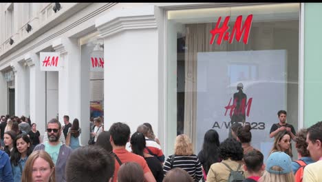Shoppers-and-pedestrians-walk-past-the-Swedish-multinational-clothing-design-retail-company-Hennes-and-Mauritz,-H-and-M-store-in-Spain