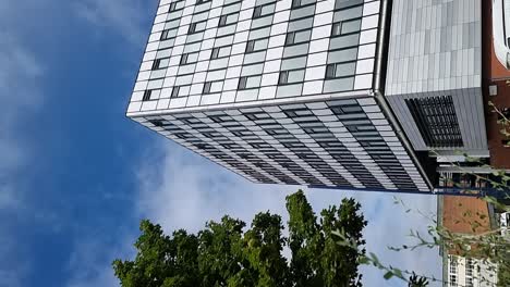 Vertikale-Glasfront-Eines-Modernen-College-Bürogebäudes-In-Der-Innenstadt,-Das-Den-Wolkenverhangenen-Blauen-Himmel-Reflektiert