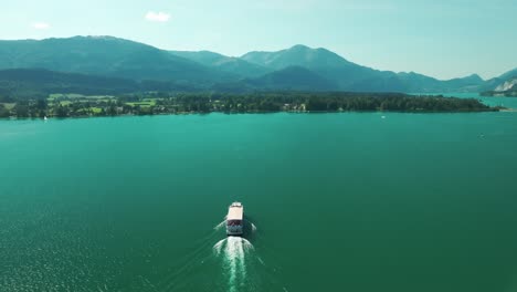 Drone-follows-a-boat-gliding-across-the-turquoise-waters-of-Wolfgangsee-lake