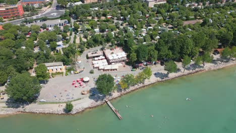 Aerial-view-waters-edge-of-Lake-Garda-in-Italy-with-trees-and-town