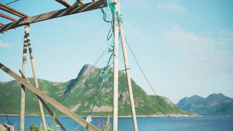 Cod-Fish-Drying-Rack-With-Net-On-The-Shore-In-Grunnfarnes,-Senja-Island,-Norway