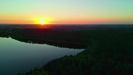 Spiegelung-Eines-Silhouettierten-Waldes-über-Einem-Friedlichen-See-Bei-Sonnenuntergang