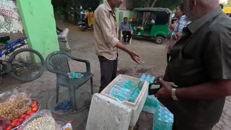 A-shopkeeper-is-selling-cold-bottles-of-water-on-the-street-road-and-taking-money-from-customers